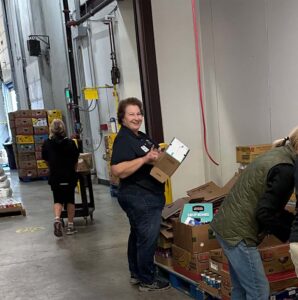 Blog - Smiling Volunteer Breaking Down Cardboard Boxes at Volunteer Day